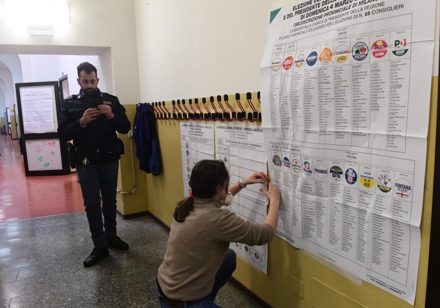 FOTO AFP-NA ELECCIONES. Una mujer publica carteles electorales y legislaci&oacute;n en una mesa electoral en Mil&aacute;n.