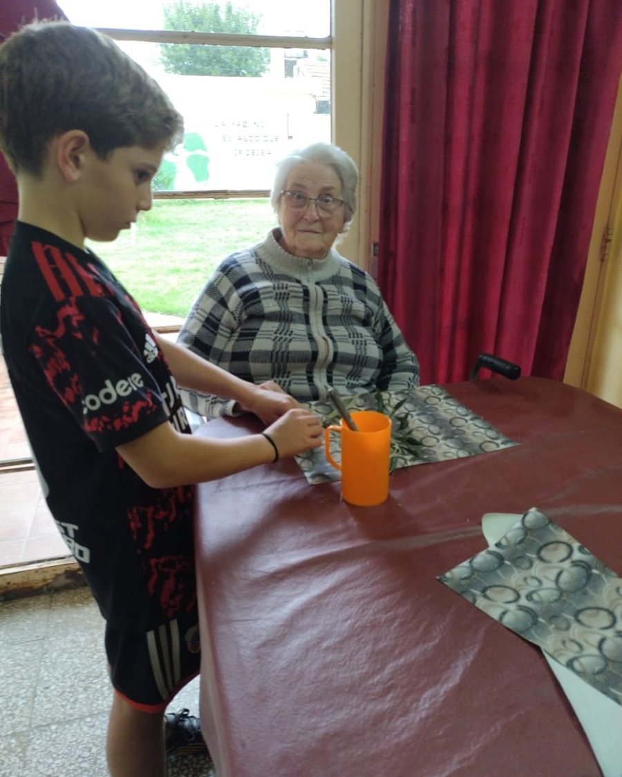 uno de los ni&ntilde;os de catequesis junto a una de las residentes en el hogar.