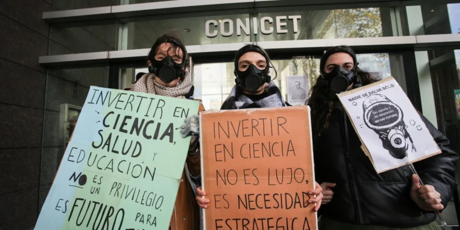Investigadoras caracterizadas como "eternautas" que enfrentan la nieve t&oacute;xica del desfinanciamiento.