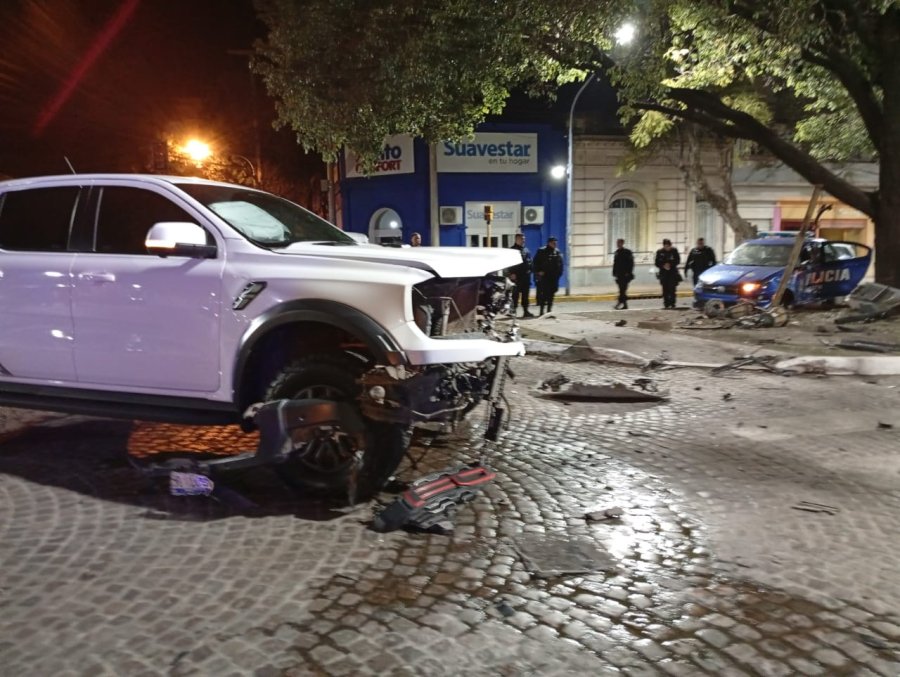 La camioneta Ford Raptor con la trompa destruida, m&aacute;s atr&aacute;s el patrullero Fiat contra un &aacute;rbol tras arrancar el sem&aacute;foro peatonal.