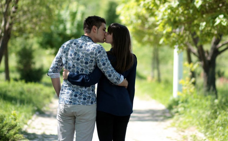 Una pareja se besa mientras pasea.